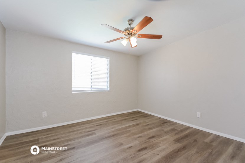 the spacious living room with ceiling fan and wood flooring