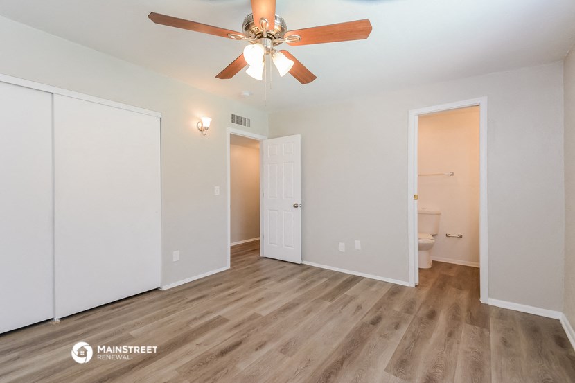 a living room with a ceiling fan and a door to a bathroom