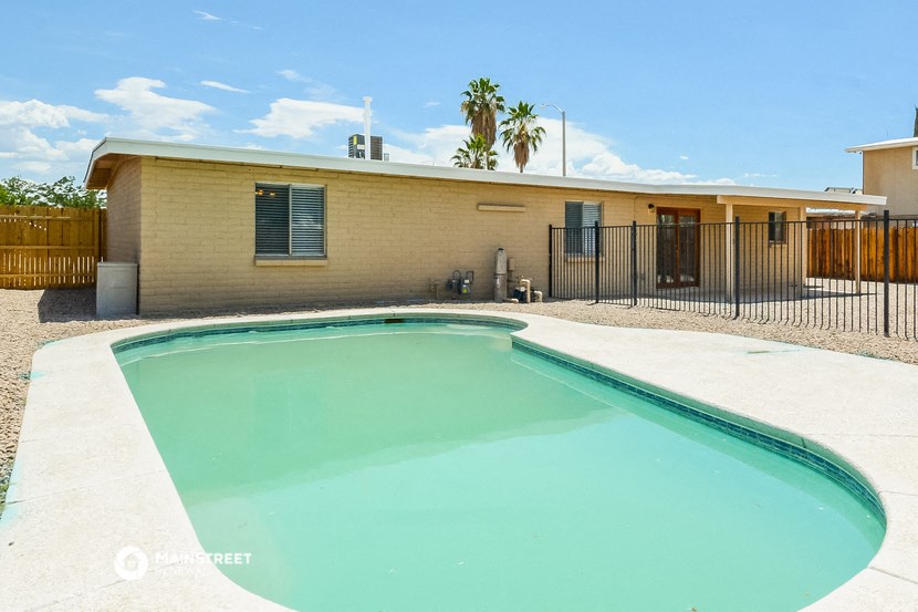 a swimming pool in front of a house with a fence