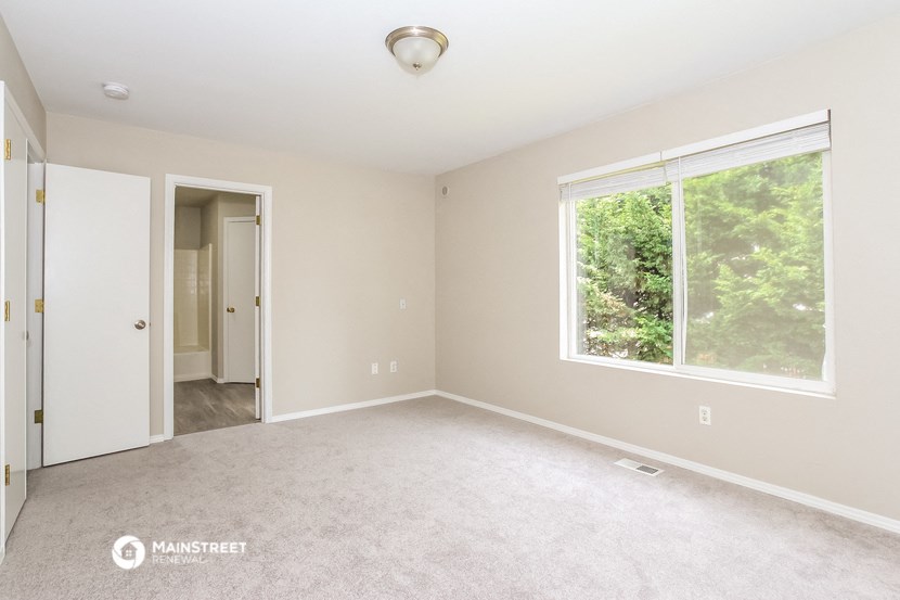 a bedroom with a large window and a carpeted floor