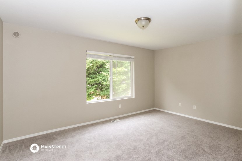 an empty bedroom with a large window and carpeting
