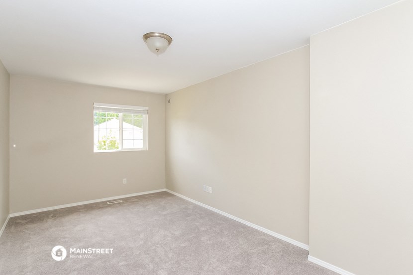the spacious living room with carpeting and a window