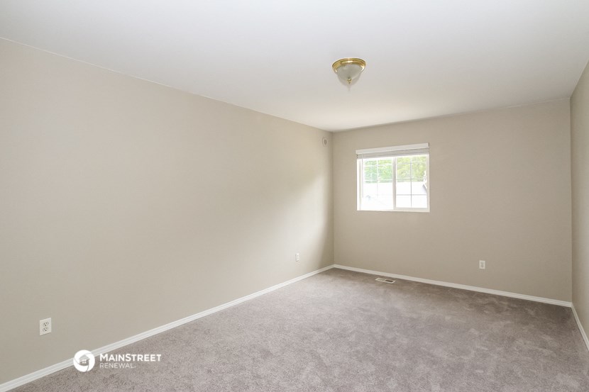 the spacious living room with carpet and a window