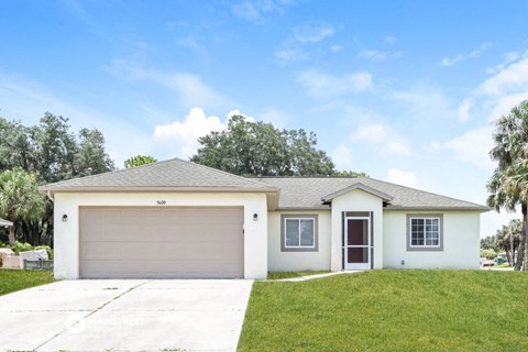 a white house with a garage door and a lawn