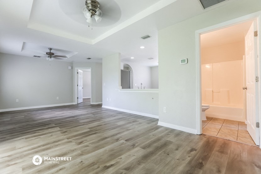 an empty living room with a ceiling fan and a bathroom