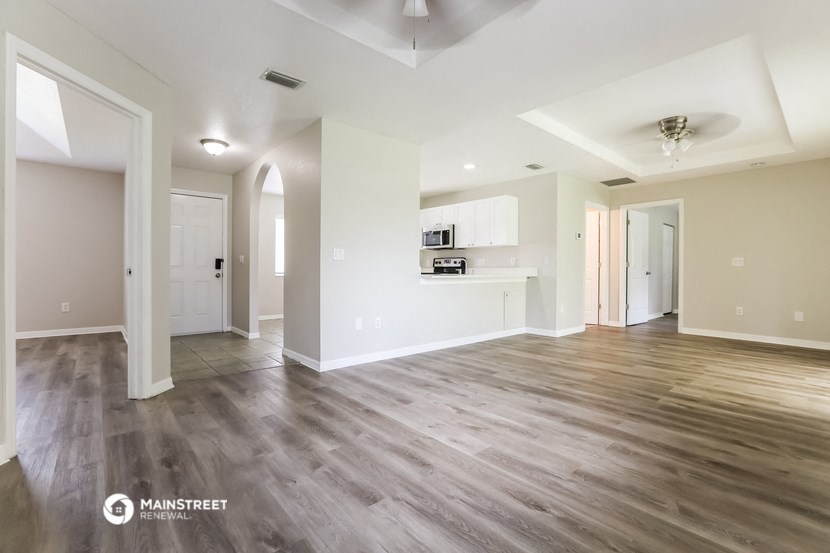 a living room and kitchen with wood flooring and white walls