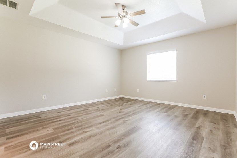 the spacious living room with wood floors and a ceiling fan
