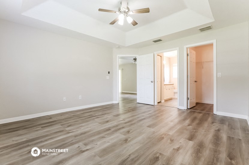 the living room of an empty house with wood flooring and a ceiling fan
