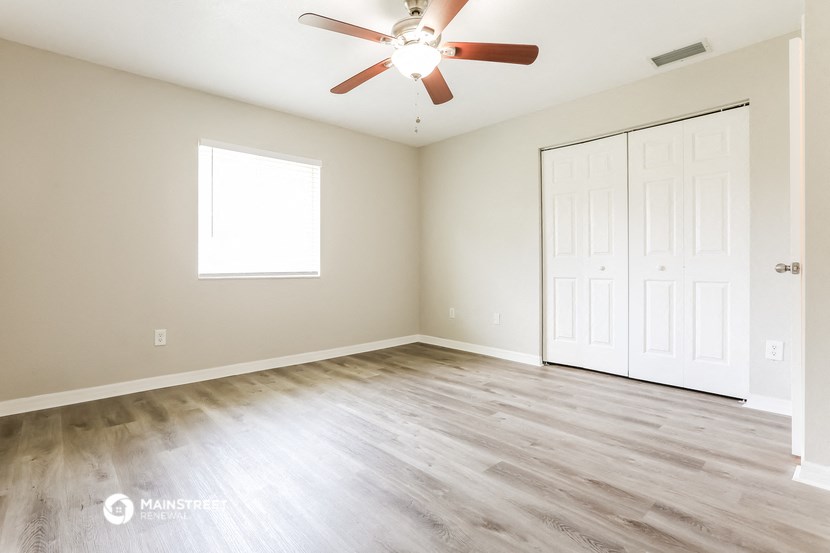 an empty living room with wood floors and a ceiling fan