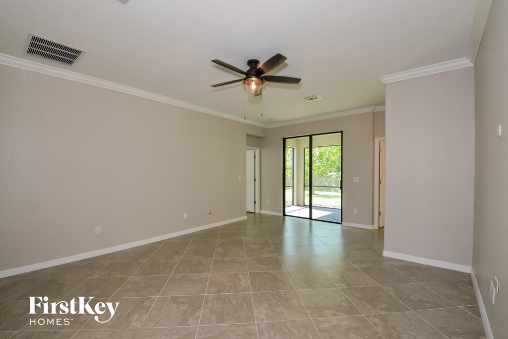 A spacious room with a ceiling fan and sliding glass doors leading to a patio.