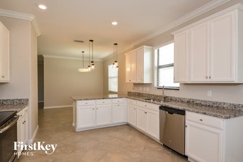 A kitchen with white cabinets and a granite countertop.