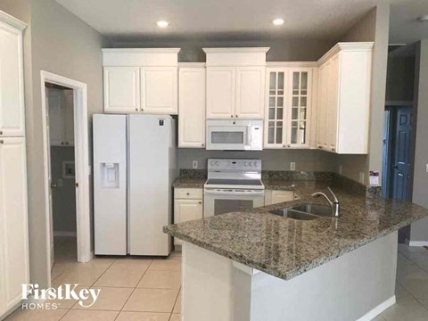 a kitchen with white cabinets and a marble counter top