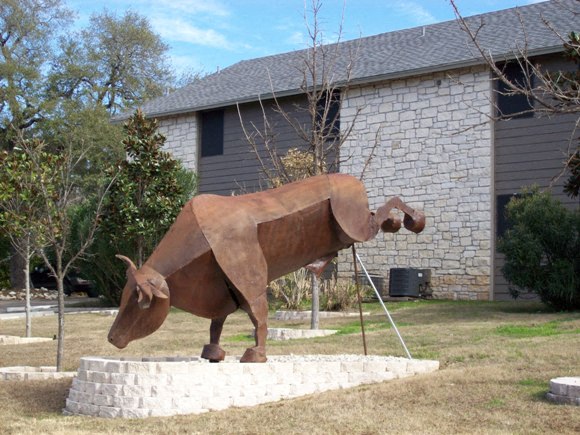 a statue of a cow in front of a house