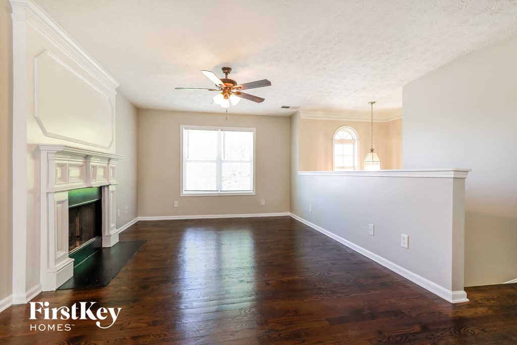 an empty living room with a fireplace and a ceiling fan