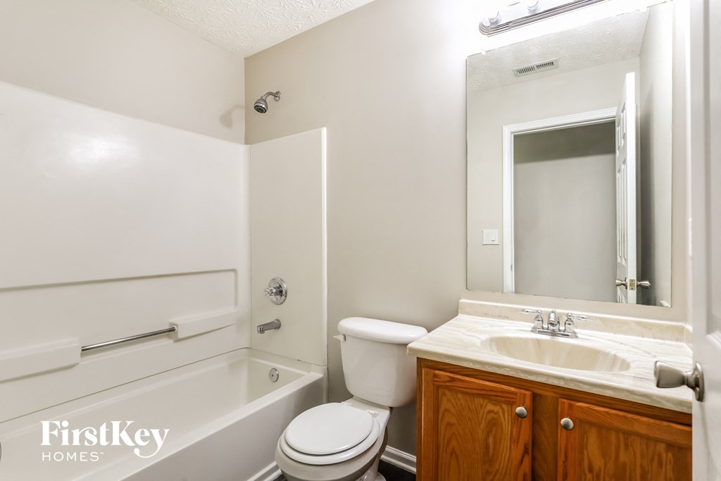 a bathroom with a toilet sink and tub and a mirror