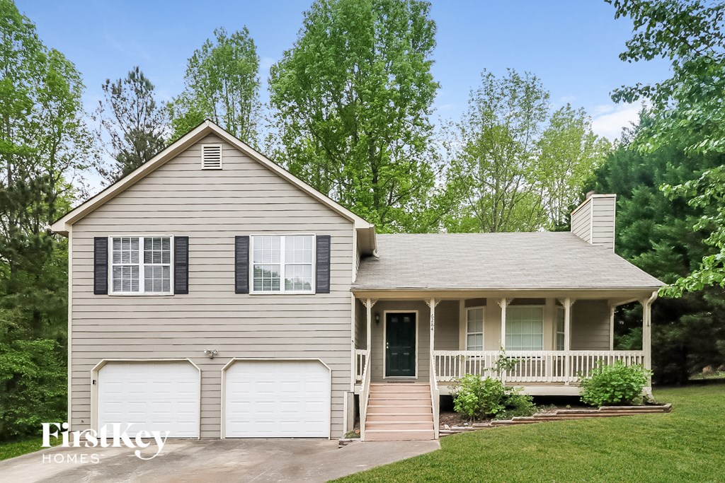A house with a grey siding and a white porch.