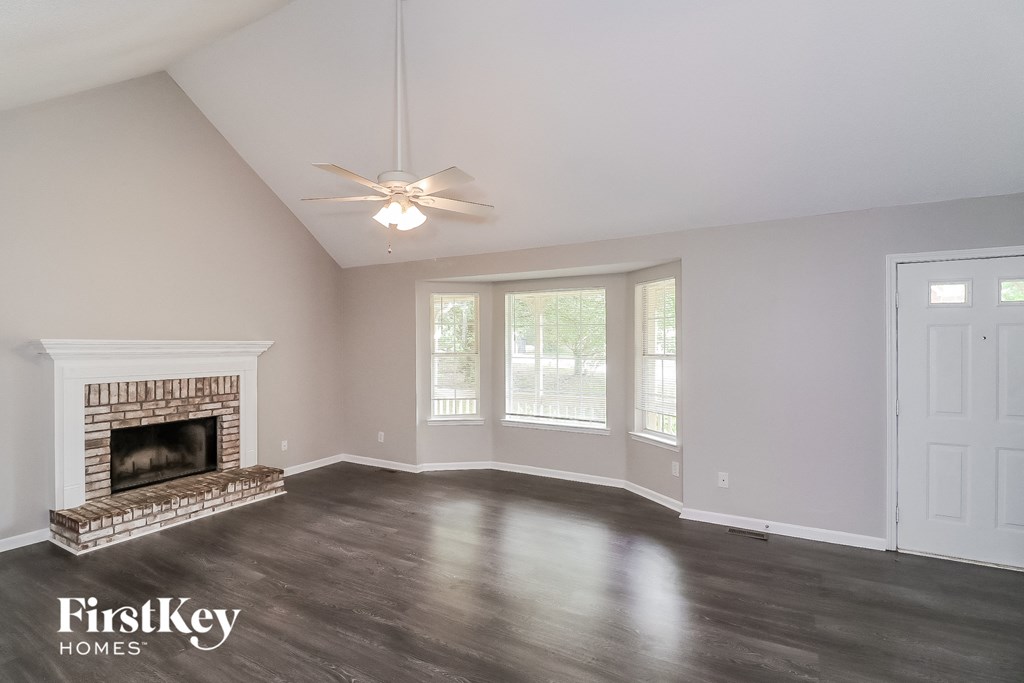 A spacious room with a fireplace and a ceiling fan.