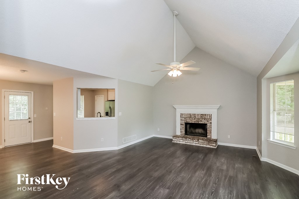 A spacious living room with a fireplace and a ceiling fan.