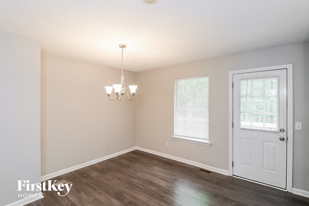 A room with a white door, a chandelier, and a window with blinds.
