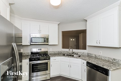 A kitchen with white cabinets and a granite countertop.