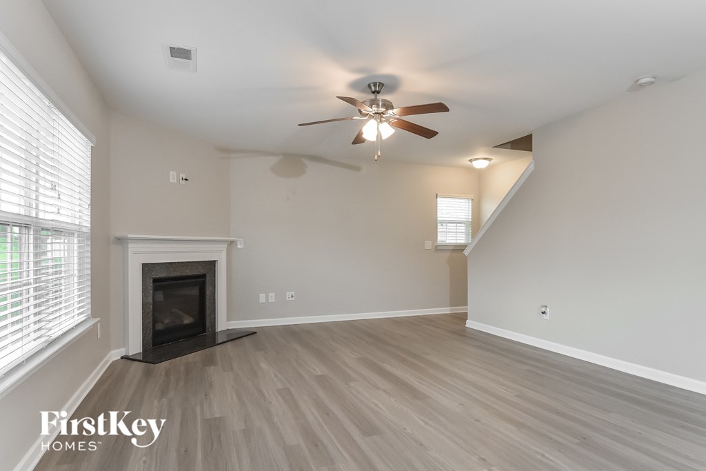 A spacious room with a fireplace and a ceiling fan.