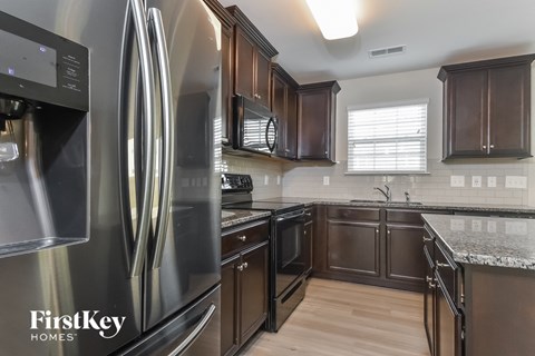 A modern kitchen with a stainless steel refrigerator and wooden cabinets.