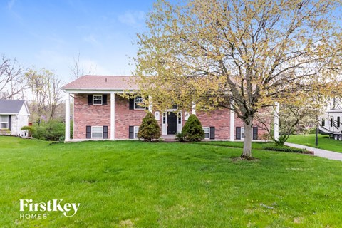a red brick house with a green lawn and a tree