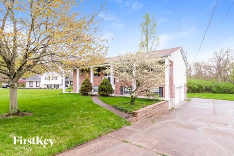 a white and brick house with a lawn and trees