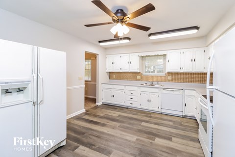 a kitchen with white cabinets and a ceiling fan