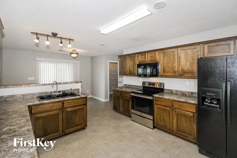 A kitchen with wooden cabinets and a black fridge.