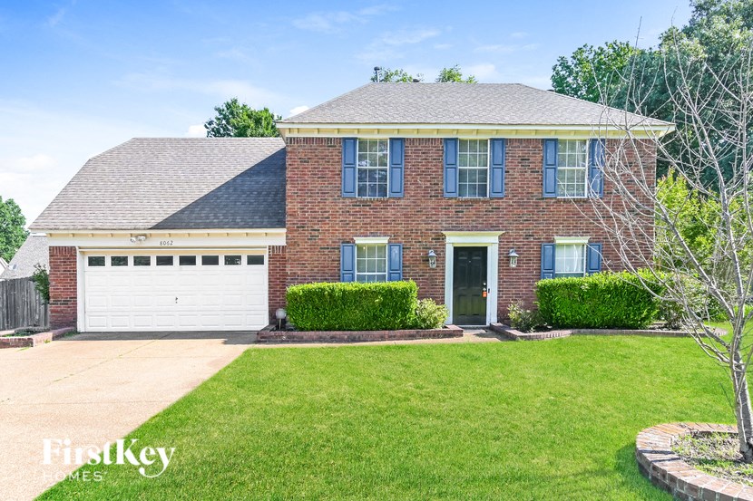 a brick house with a green lawn and a white garage door