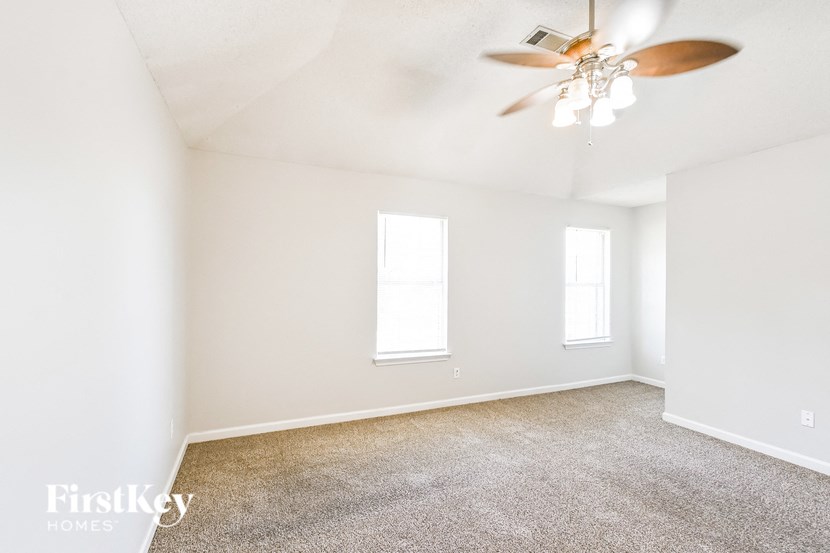 a living room with white walls and a ceiling fan