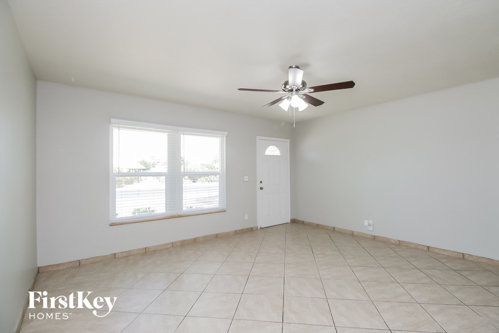 A spacious room with a ceiling fan and a door leading to another room.