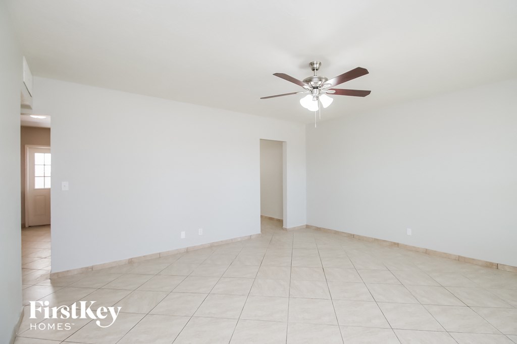 A spacious room with a ceiling fan and tiled flooring.
