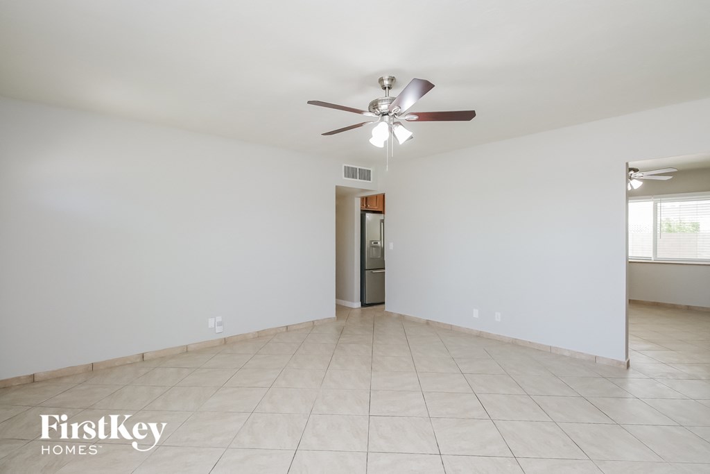A spacious room with a ceiling fan and a door leading to another room.