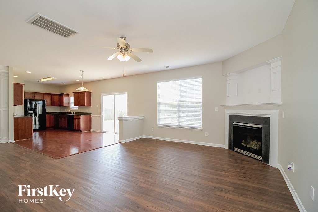 A spacious living room with wood flooring and a fireplace.