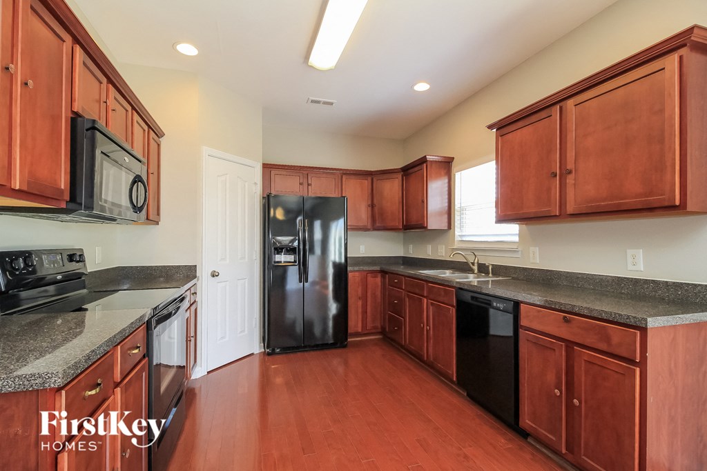 A kitchen with wooden cabinets and a black refrigerator.