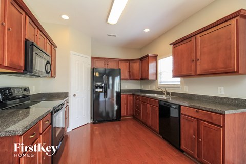 A kitchen with wooden cabinets and a black refrigerator.