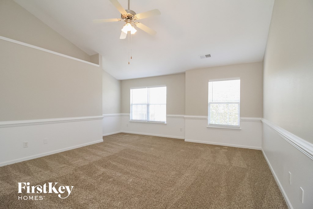 A spacious room with a carpeted floor and a ceiling fan.
