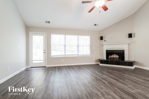 A spacious room with a fireplace and a ceiling fan.