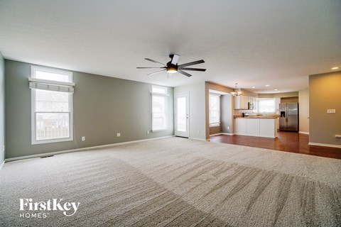 an empty living room with a ceiling fan and a rug