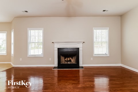 A living room with a fireplace and two windows.