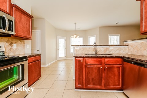 A kitchen with red cabinets and a black stove top oven.