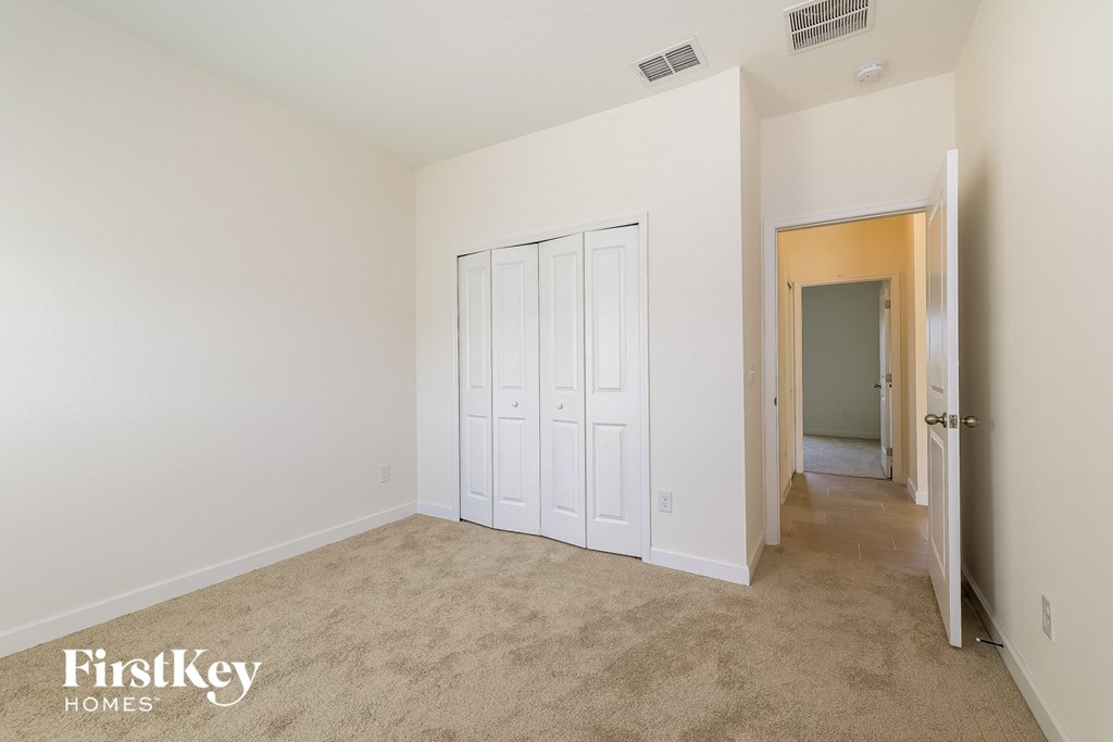 A bedroom with a white closet and carpeted floor.