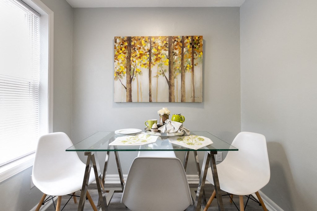 a dining room with a table and chairs and a painting on the wall