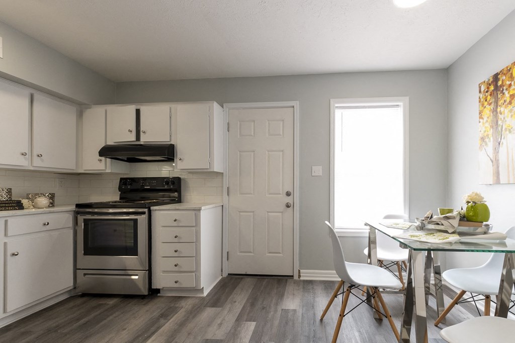a kitchen with white cabinets and stainless steel appliances and a table