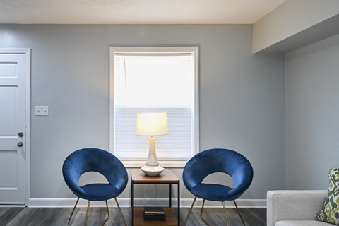 two blue chairs in a living room with a window
