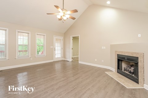 A spacious living room with a fireplace and a ceiling fan.