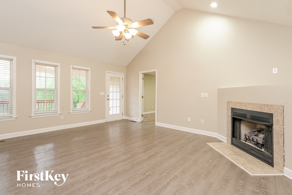 A spacious living room with a fireplace and a ceiling fan.