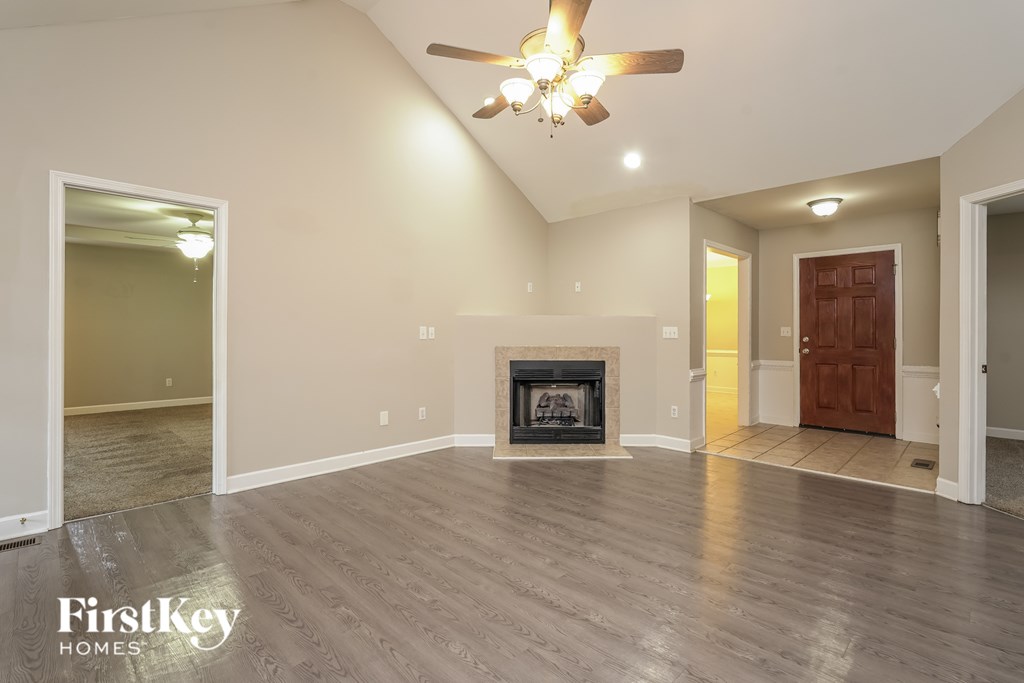 A spacious living room with a fireplace and a ceiling fan.